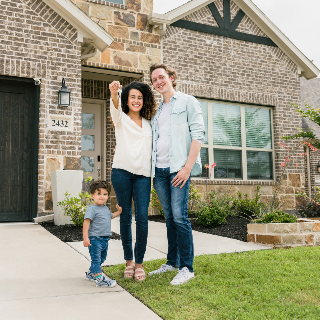 Happy family in front of new house holding up keys.